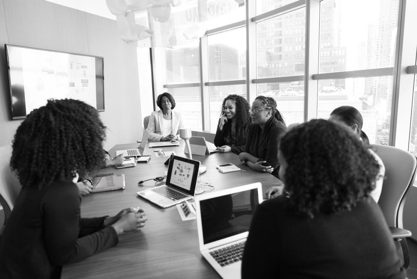 Professionnelles échangeant autour de leurs ordinateurs en salle de réunion